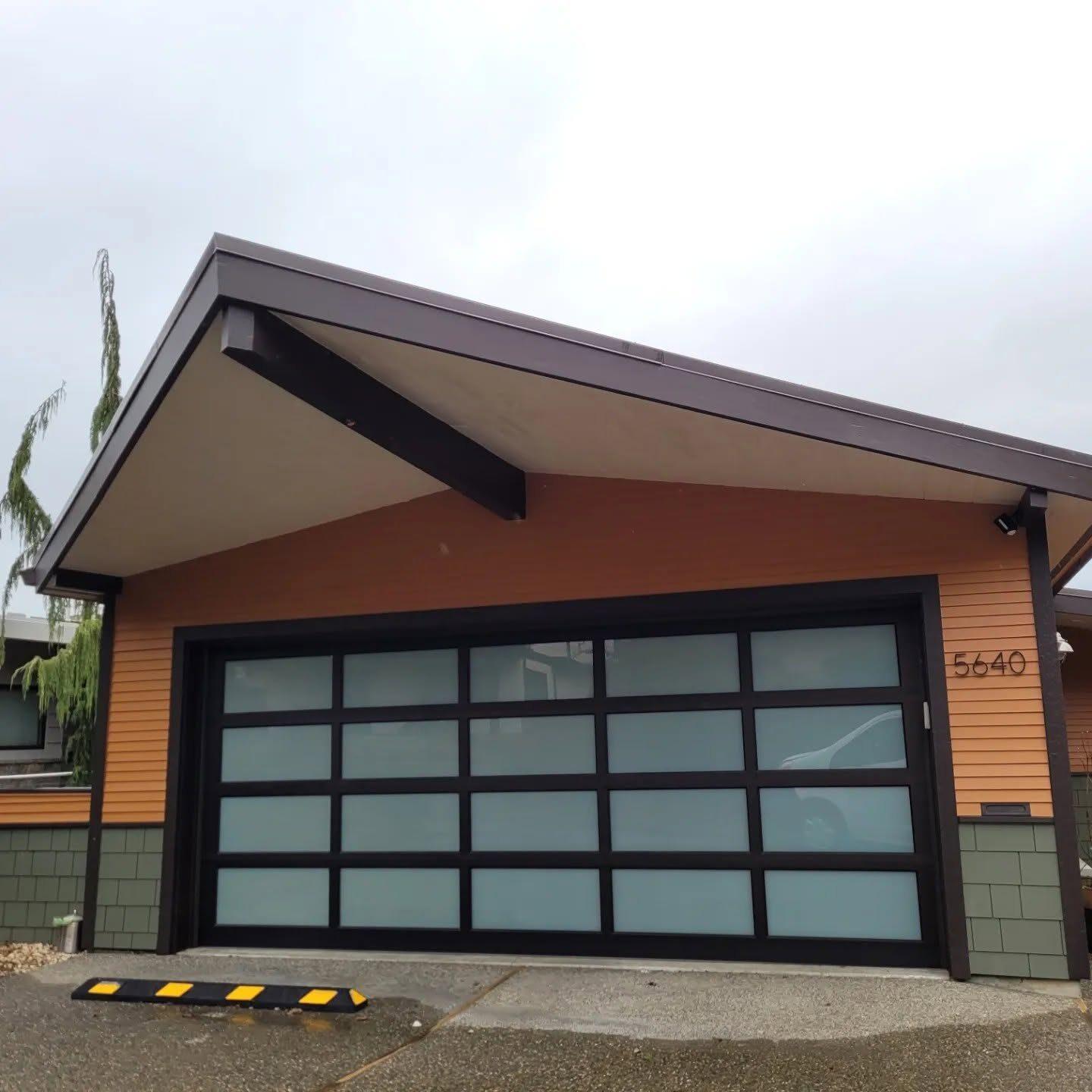 Detached garage with a glass roll-up door and cedar siding