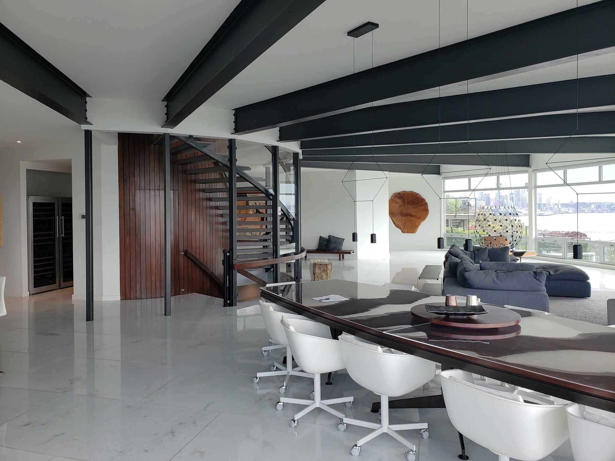 Modern great room with stone floors, wood accent wall and floating stair
